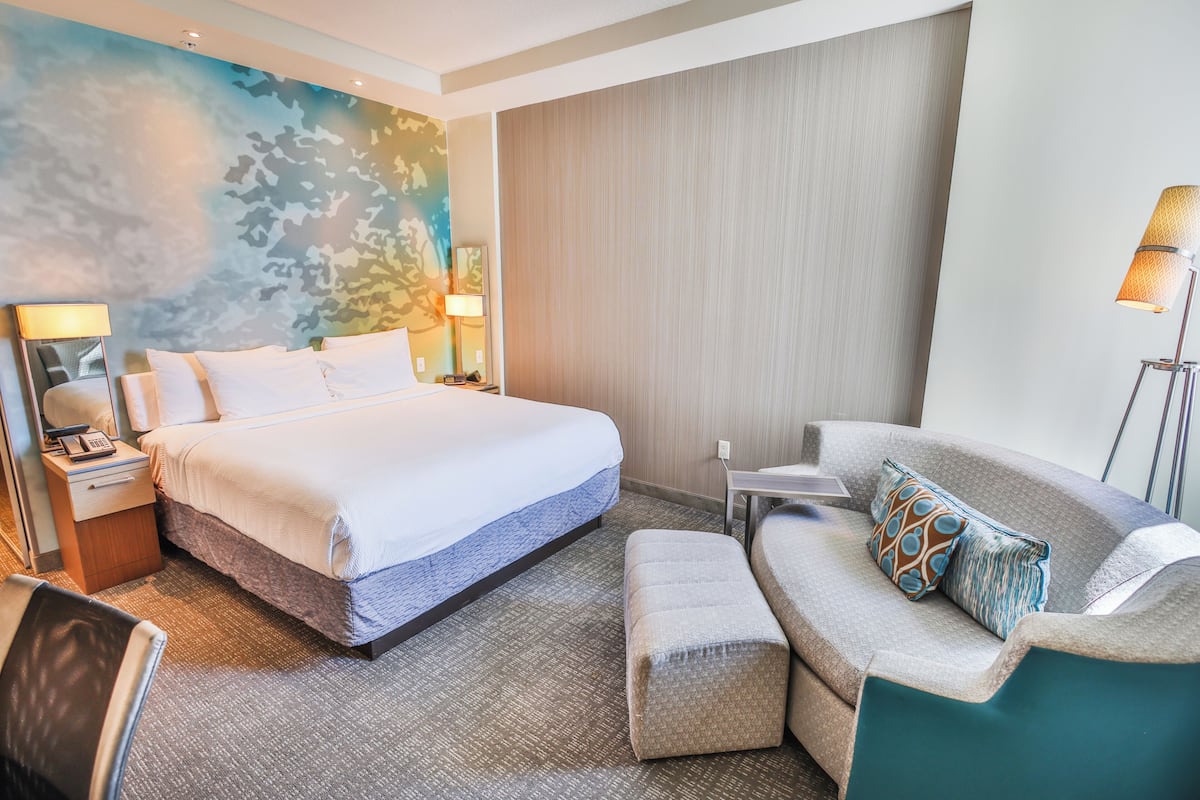 Een hotelkamer met een bed, een bank, een bureau en een lamp.
