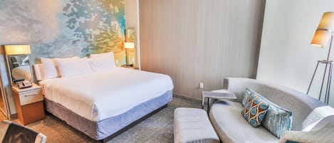 Ett hotellrum med en sÀng, en soffa, ett skrivbord och en lampa.