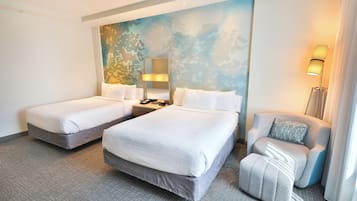 A hotel room with two beds, a chair, a nightstand, and a wall mural.
