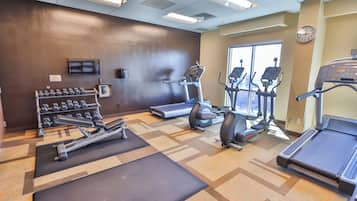A gym with treadmills, elliptical machines, and dumbbells.