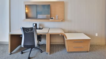 Un escritorio moderno con una televisión de pantalla plana, una silla y un estante pequeño con un vaso y un dispositivo.