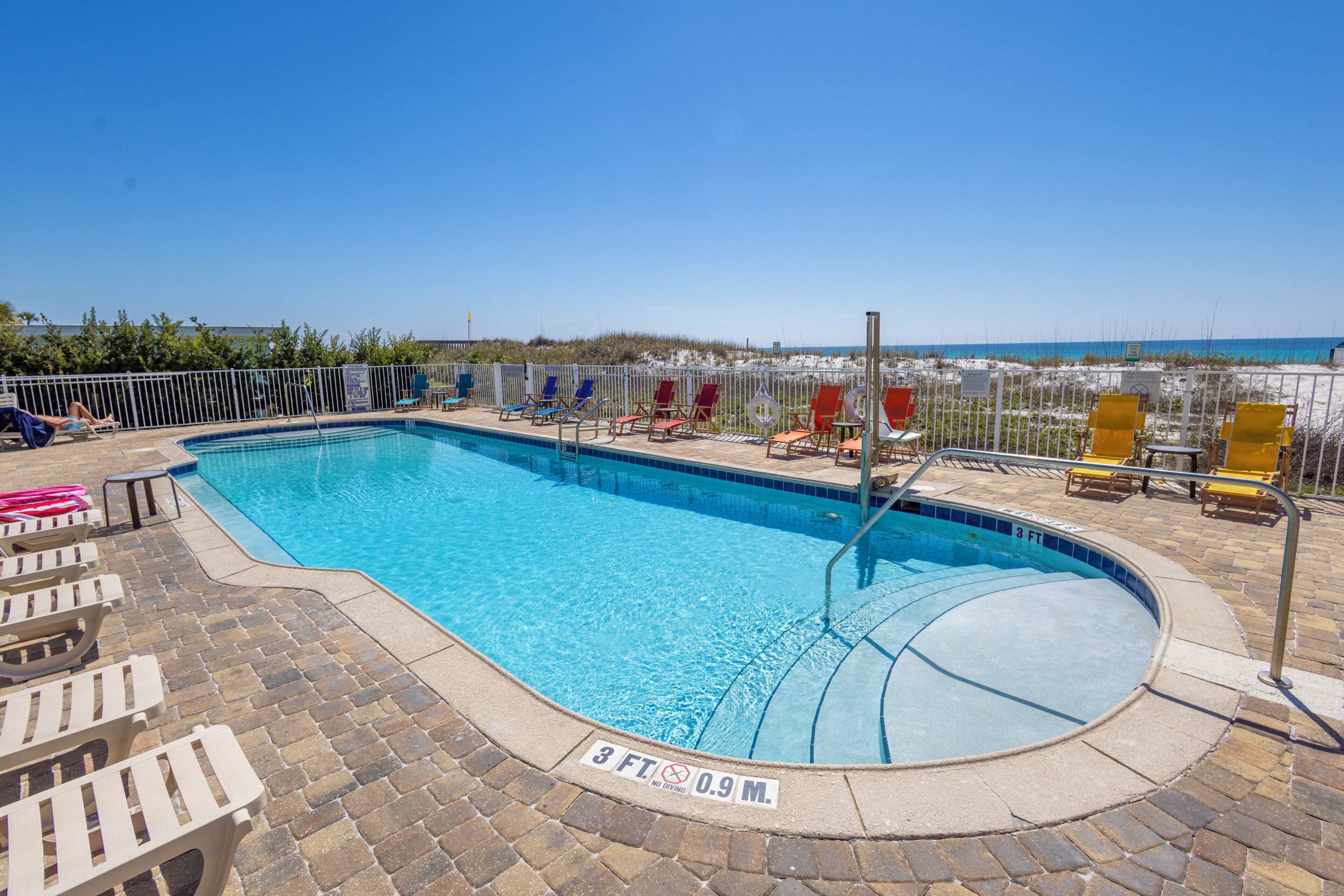 A swimming pool with a 3 FT depth sign, surrounded by lounge chairs and a brick deck.