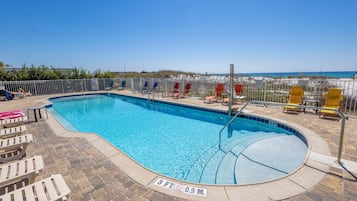 A swimming pool with a 3 FT depth sign, surrounded by lounge chairs and a brick deck.