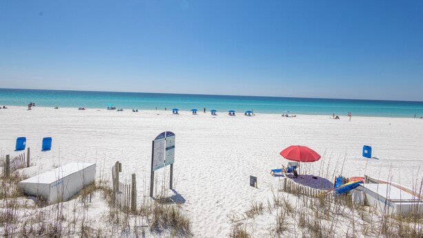A beach with clear skies, a sandy shore, and a few beach umbrellas.