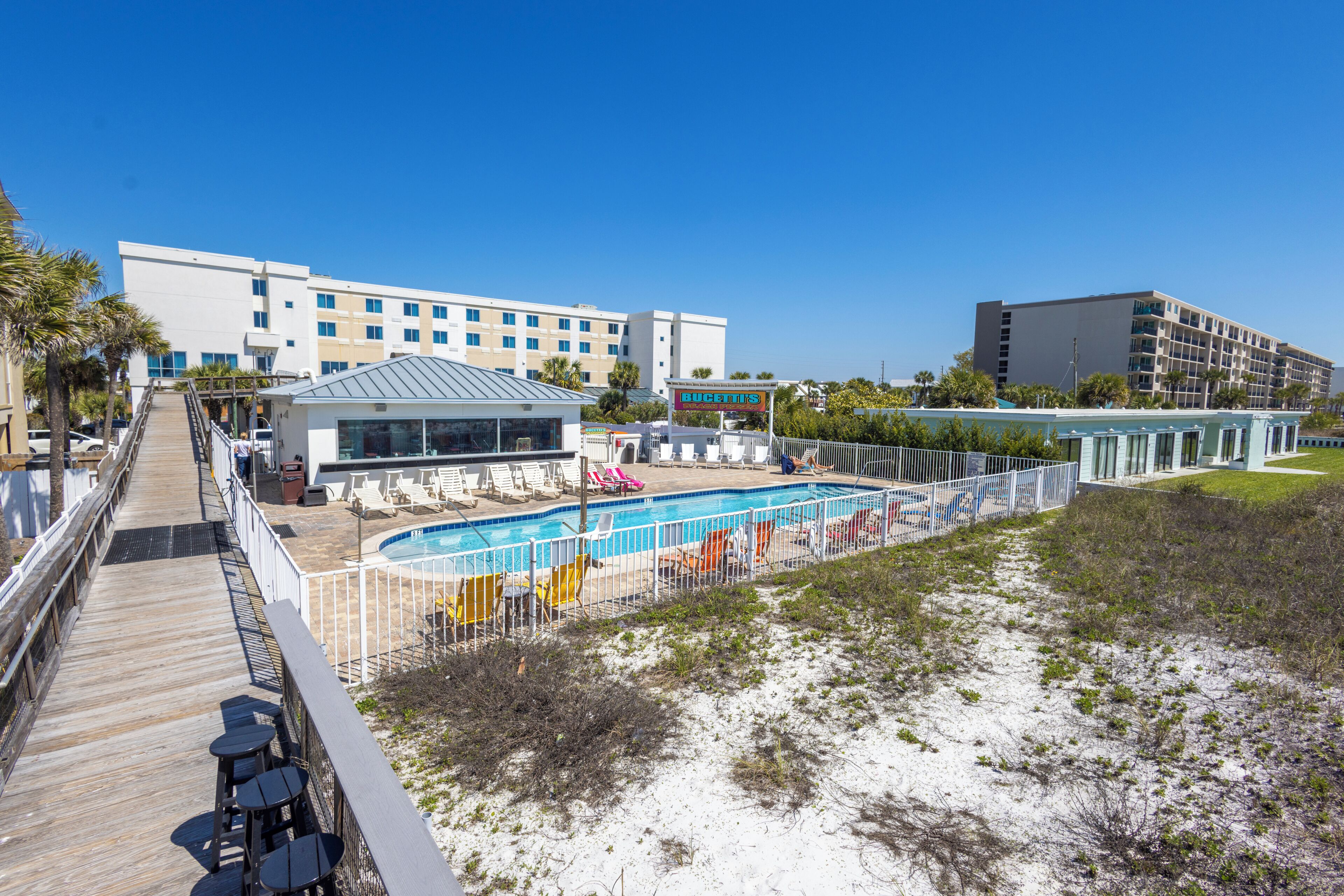 Un hotel con piscina, zona de estar al aire libre y paseo marítimo.