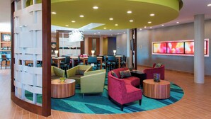 A modern lobby with a curved ceiling, seating areas, a reception desk, and a large digital display.