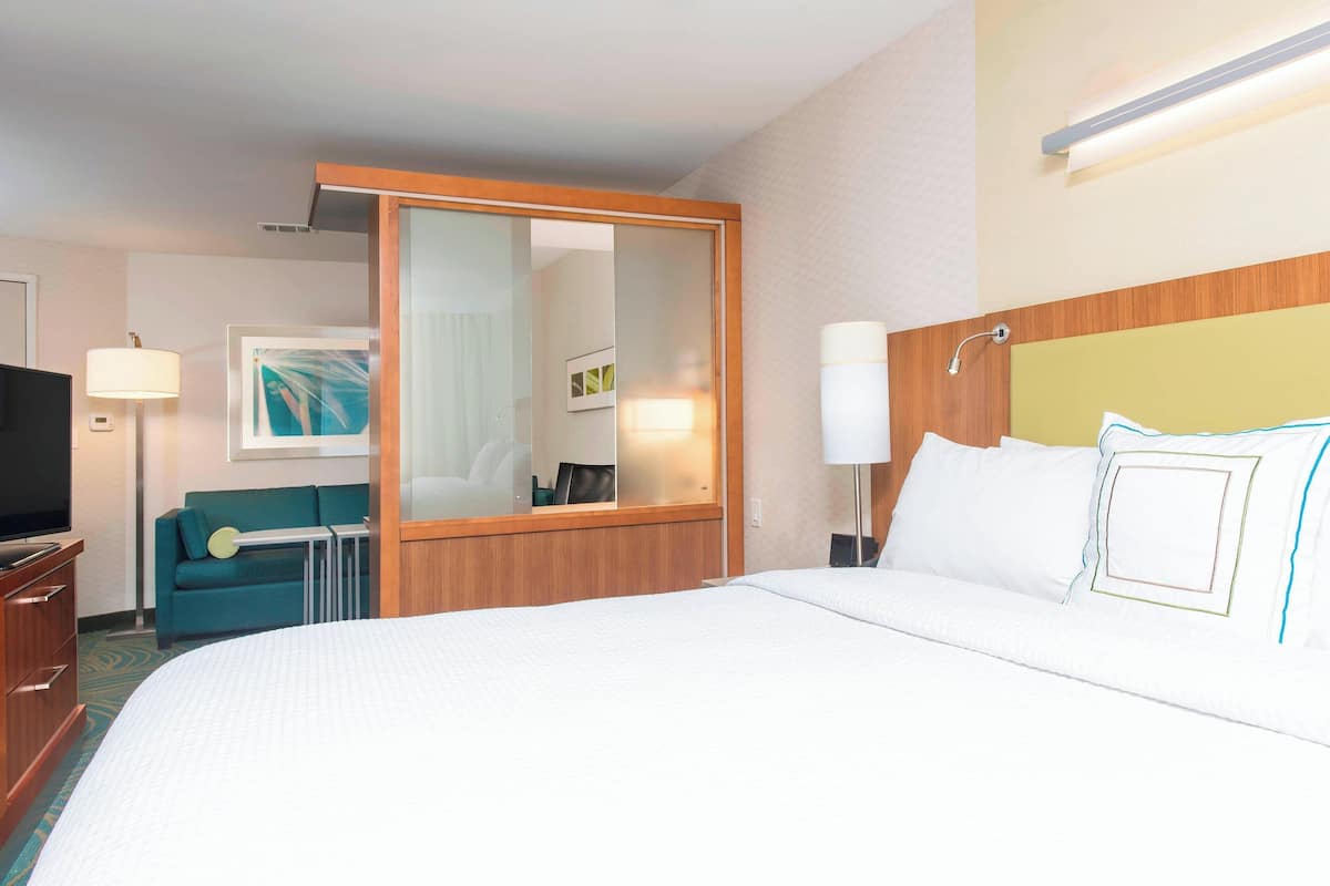 A hotel room with a large bed, a television, a sofa, and a desk.