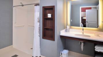 Un baño moderno con ducha, lavamanos, espejo y toallero.