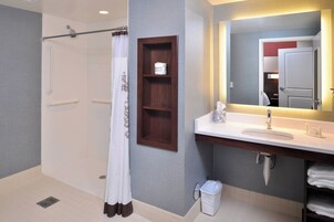 Un baño moderno con ducha, lavamanos, espejo y toallero.