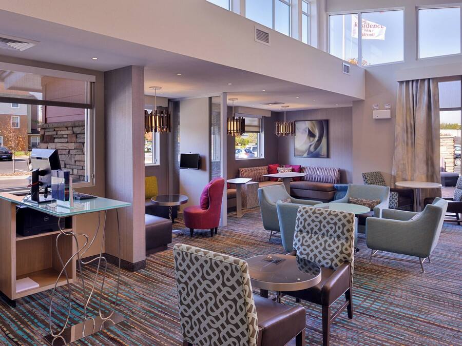 A hotel lobby with seating areas, a reception desk, and large windows.