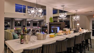 Una cocina moderna con una isla grande, taburetes de bar y un comedor con vistas a la ciudad de noche.