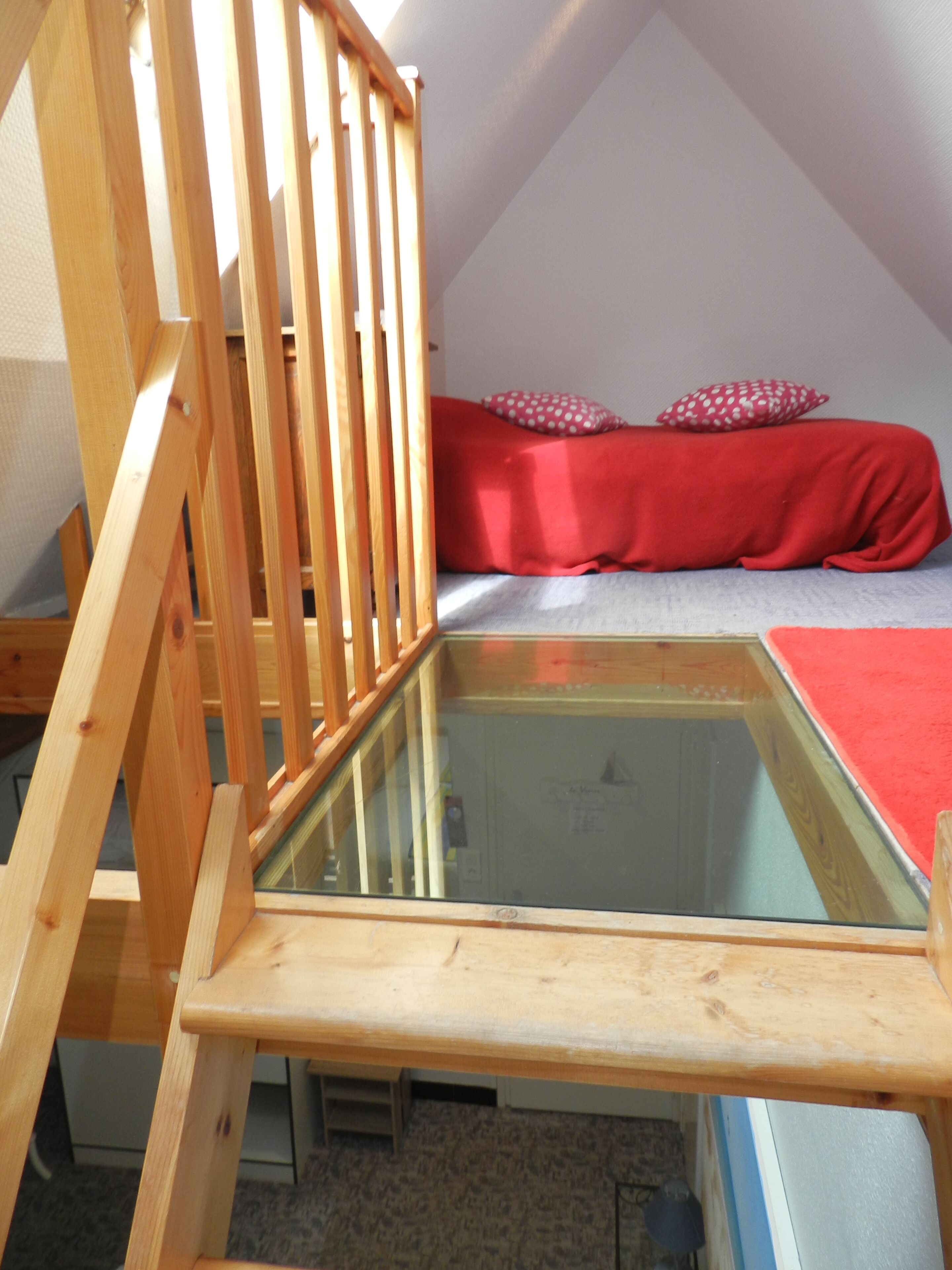 A wooden chair with a glass seat in a room with a sloped ceiling.