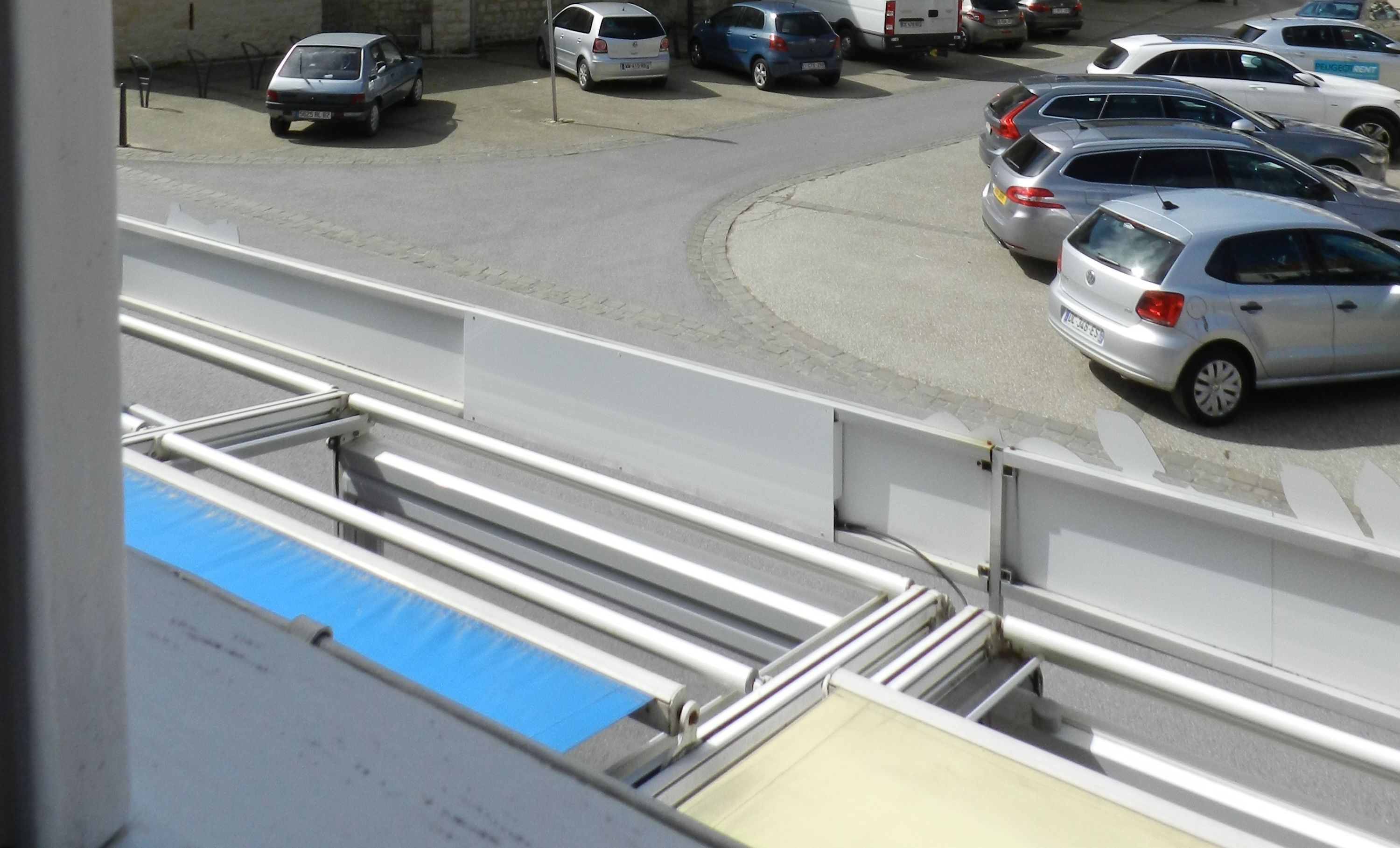 Een parkeerplaats met meerdere auto's, waaronder een witte bus en verschillende personenauto's.