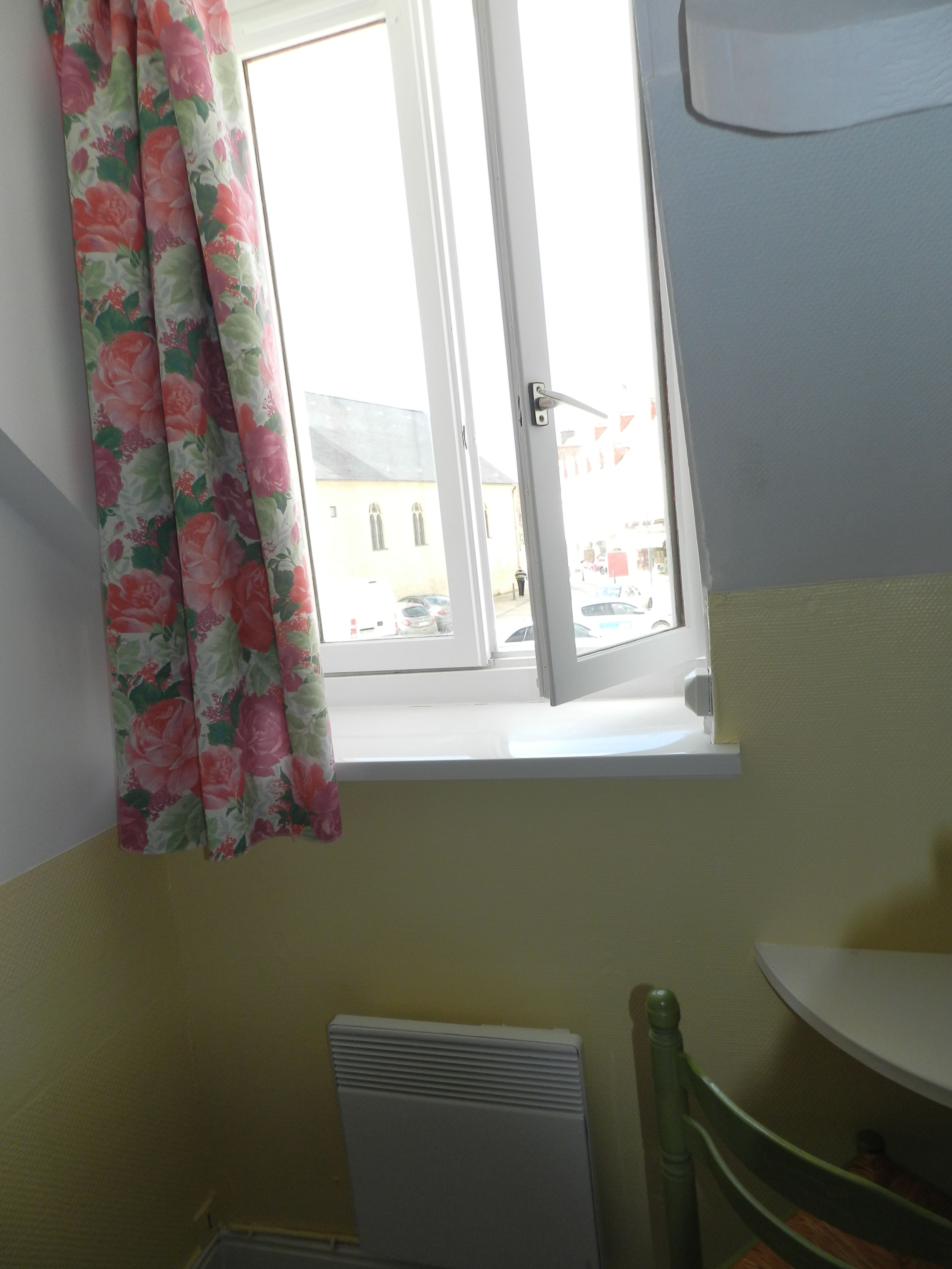 A room with a window, a radiator, and a chair.