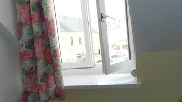 Una habitación con ventana, radiador y una silla.
