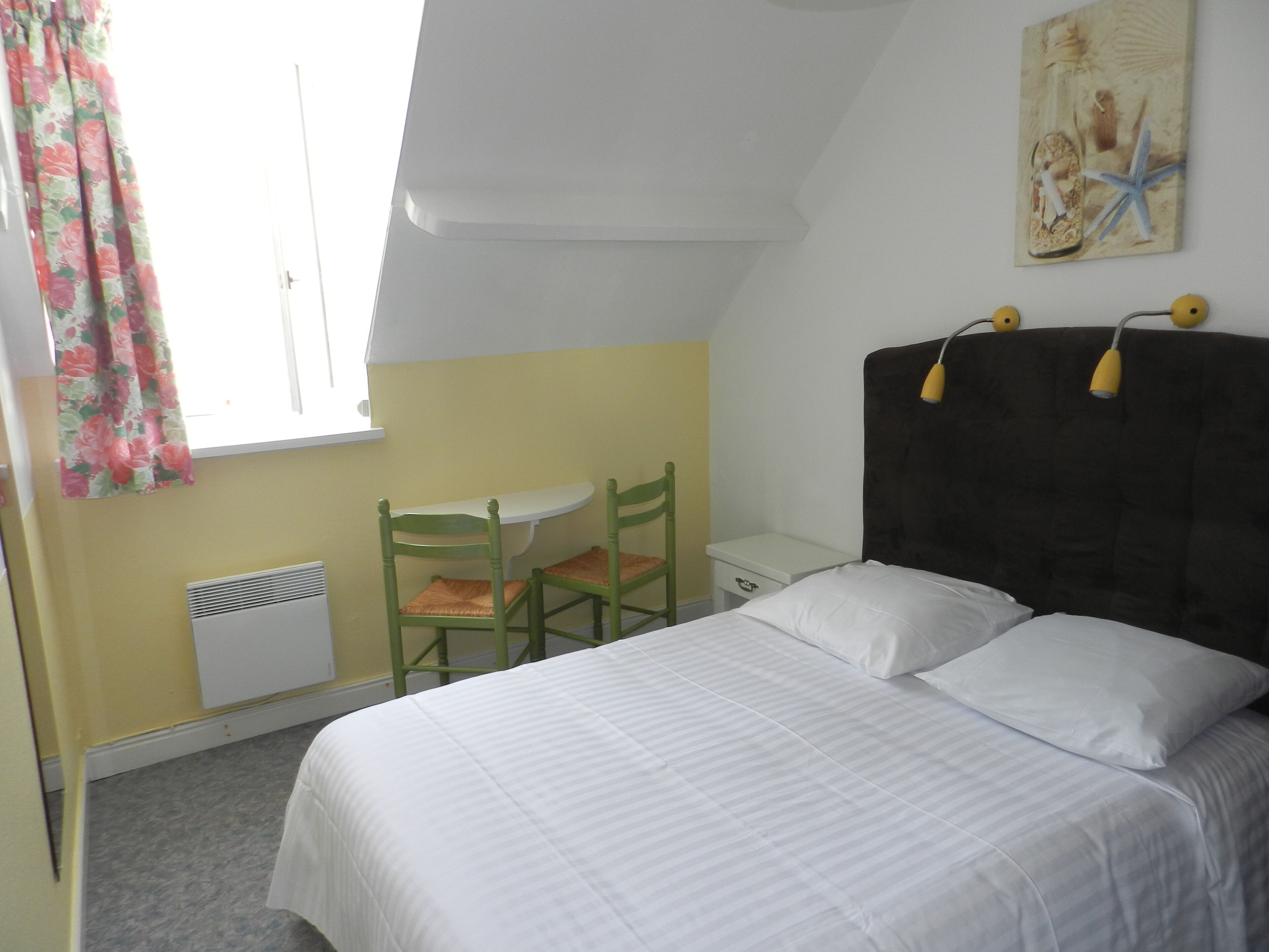 Een slaapkamer met een bed, een bureau en een stoel.