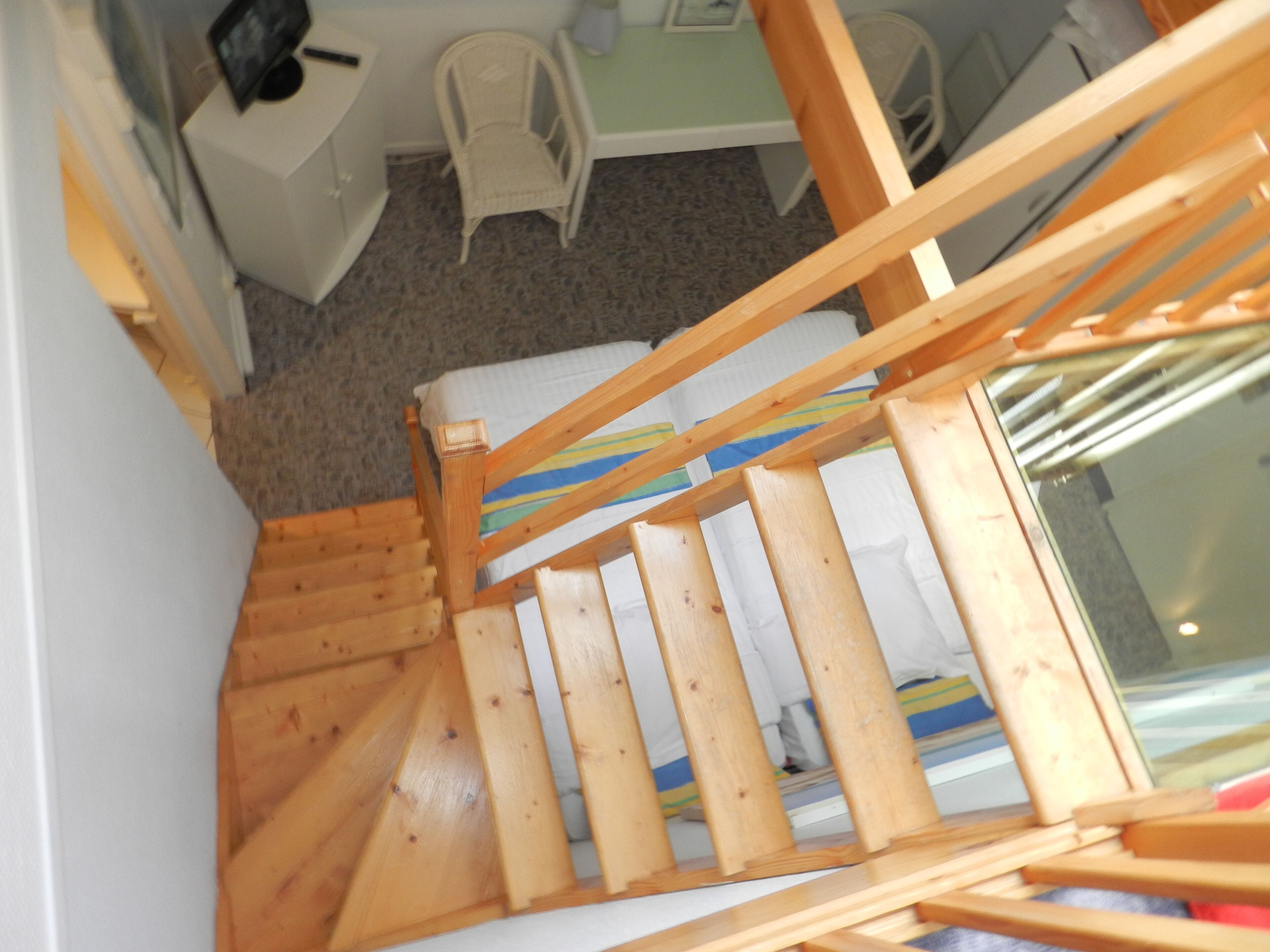 A wooden staircase with a white cushion at the bottom.