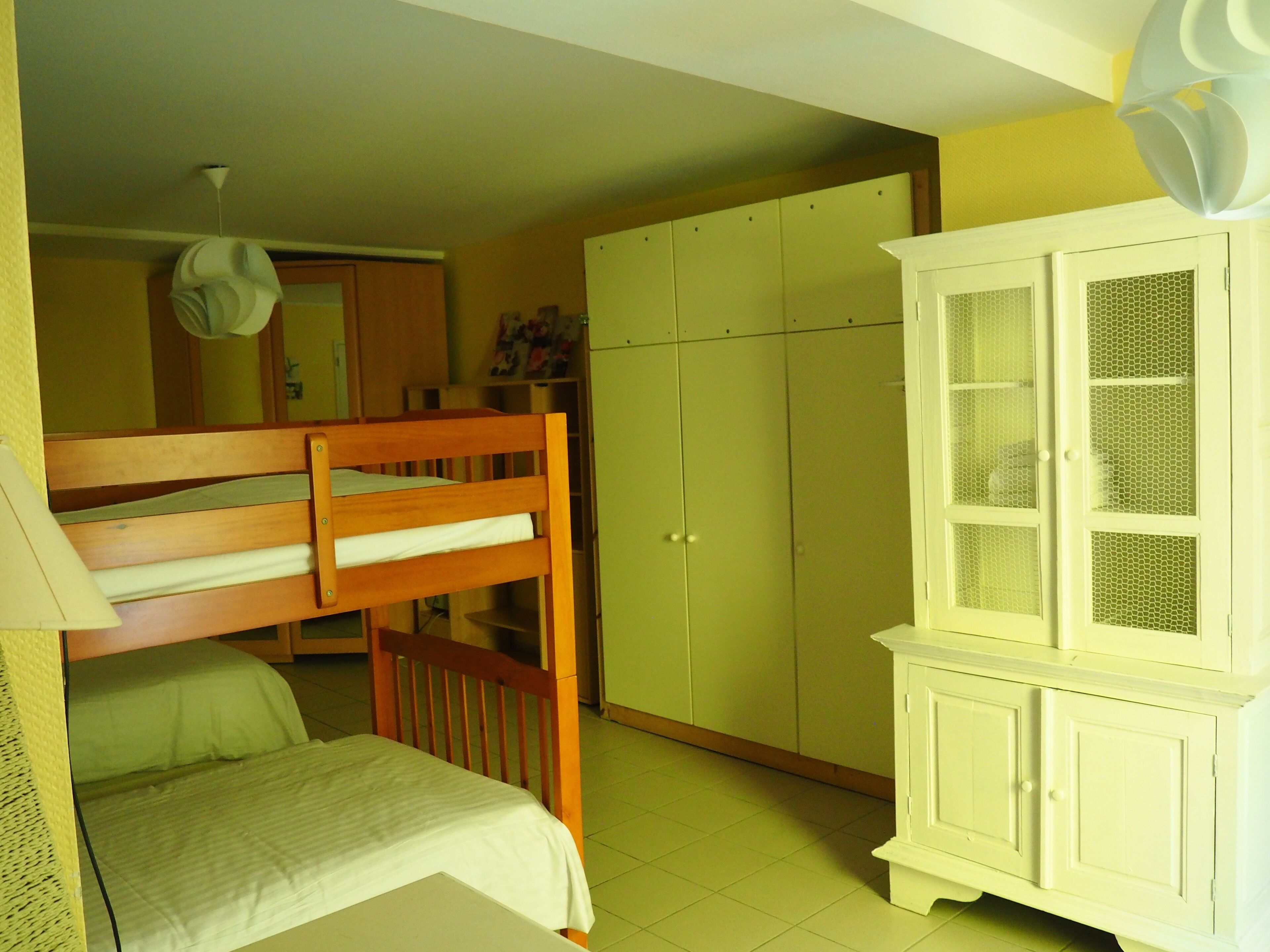 Um quarto com beliches, um guarda-roupa e um armário.