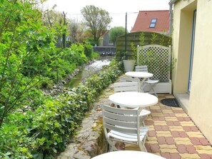 A patio area with a small stream, white outdoor furniture, and a lattice fence. - Hôtel Le Vivier WISSANT - Centre Village (Wissant)