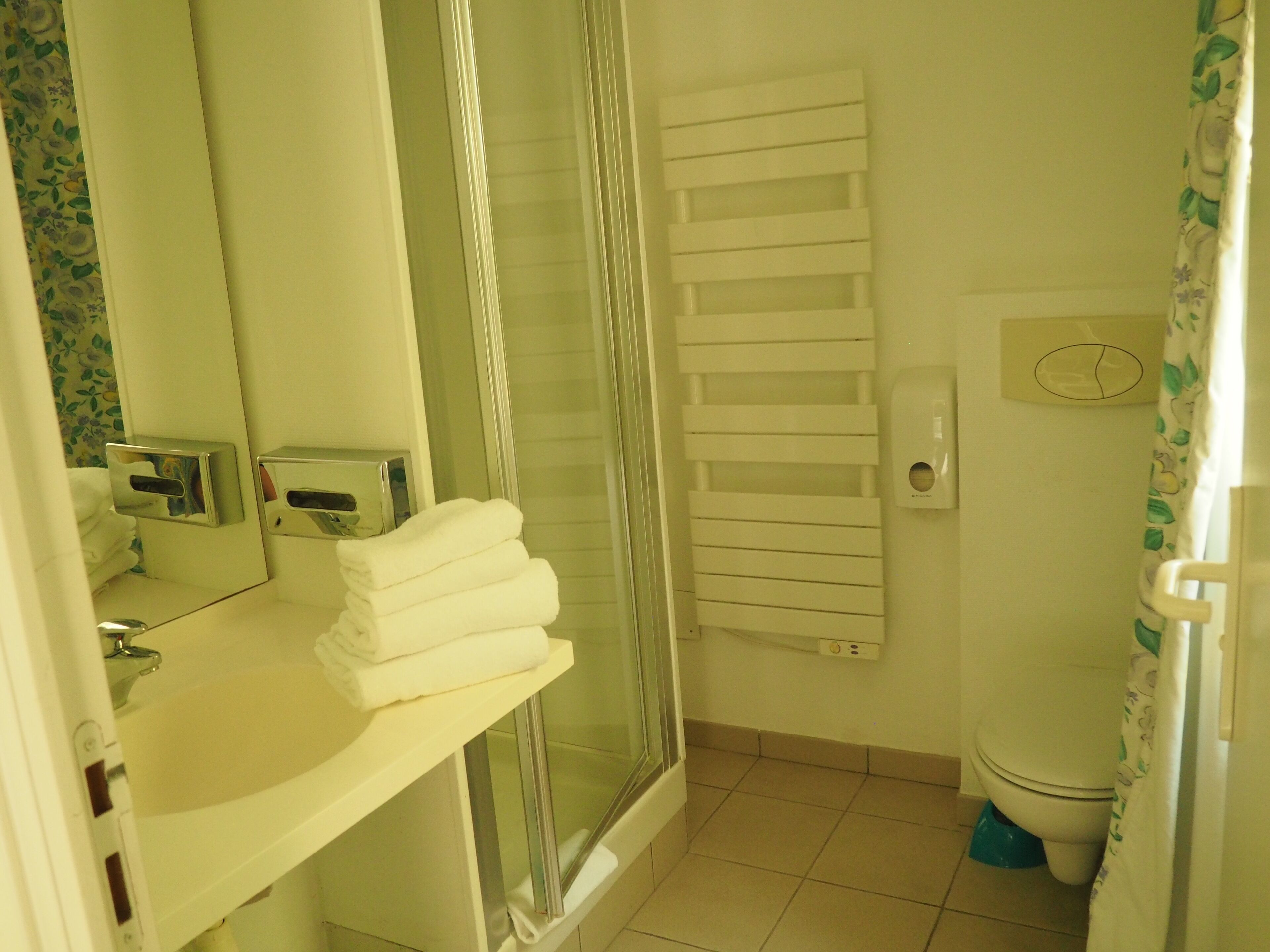 Casa de banho com cabine de chuveiro em vidro, sanita branca e lavatório com espelho.