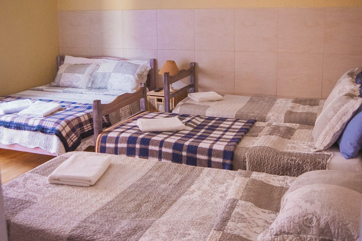 A bedroom with two beds, a ceiling fan, and an air conditioning unit.