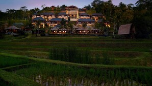 A large resort with multiple buildings, a water body in the foreground, and lush greenery.