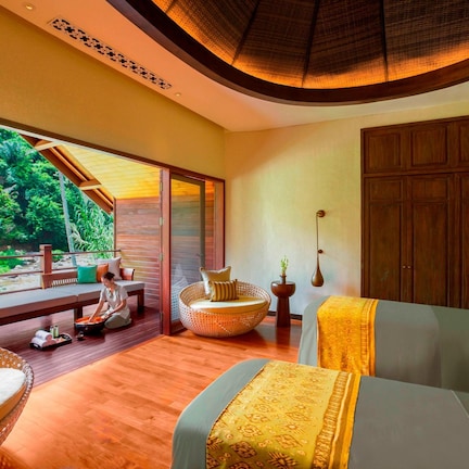 A room with a large window, a bed, a sofa, and a wooden cabinet.