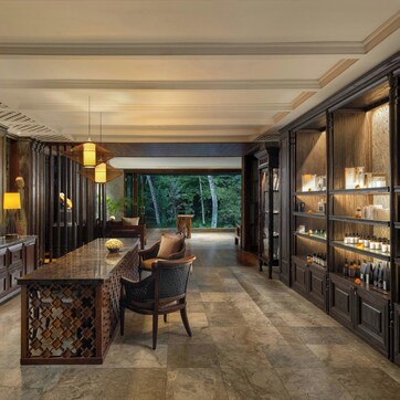 Un lobby de hotel espacioso con piso de mármol, paneles de madera, una zona de bar central y vistas al exterior.