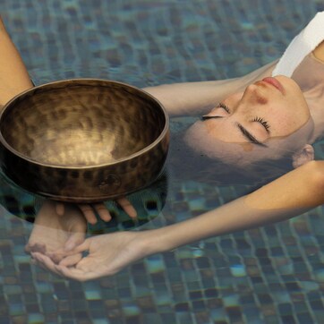 A person lying in a pool holding a bowl.