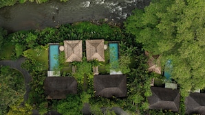 An aerial view of a resort with three pools, surrounded by lush greenery and a river. - Mandapa, a Ritz-Carlton Reserve (Ubud)