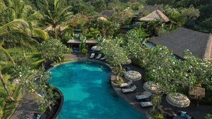 A resort with a large swimming pool, lounge chairs, and tropical vegetation.