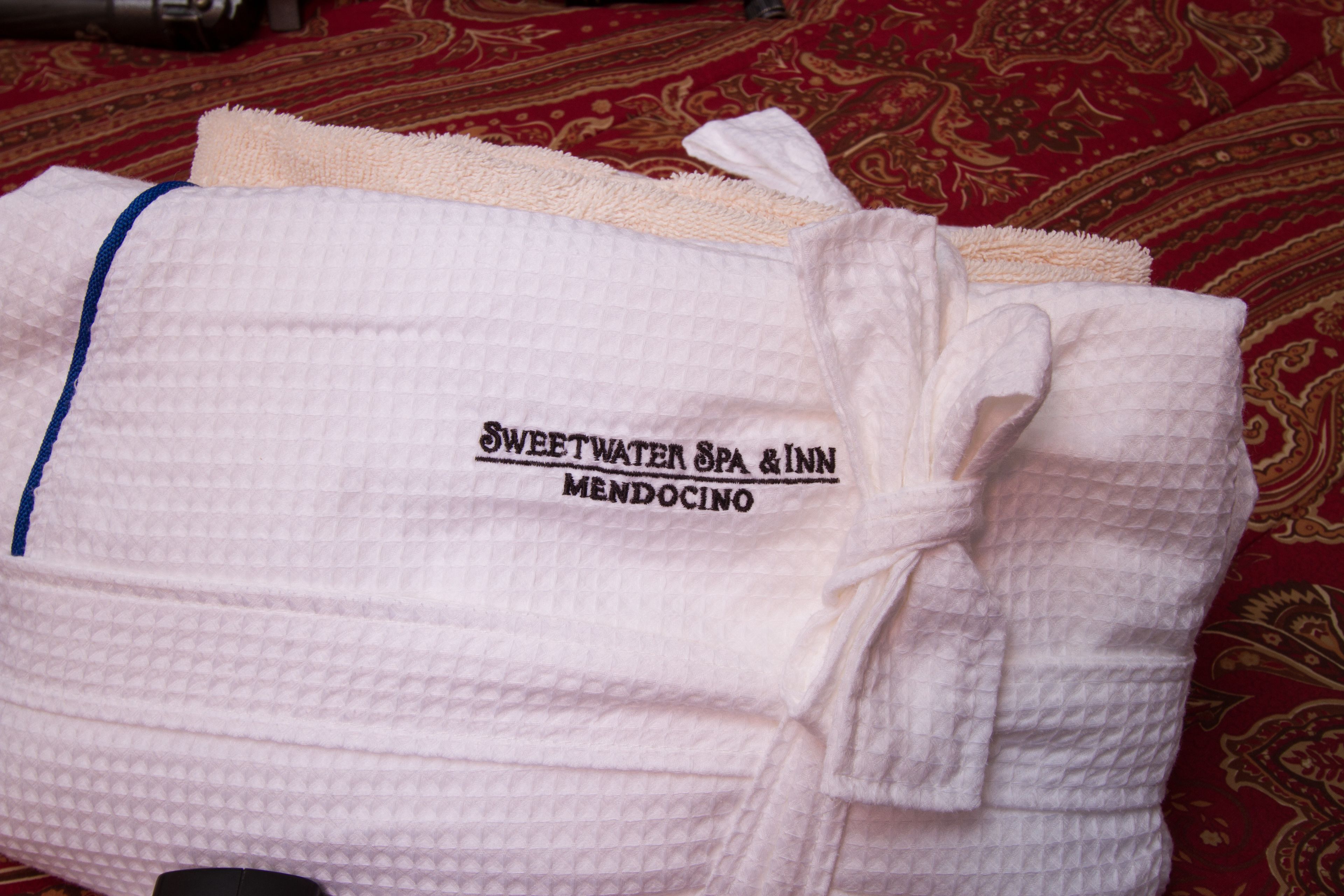 A folded white towel with a blue edge and a label that reads "Sweetwater Spa & Inn Mendocino."