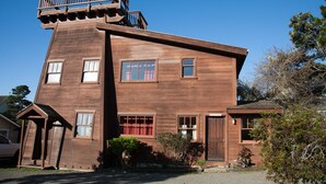 Un edificio de madera de dos pisos con un balcón en el nivel superior, una puerta principal y un pequeño porche.