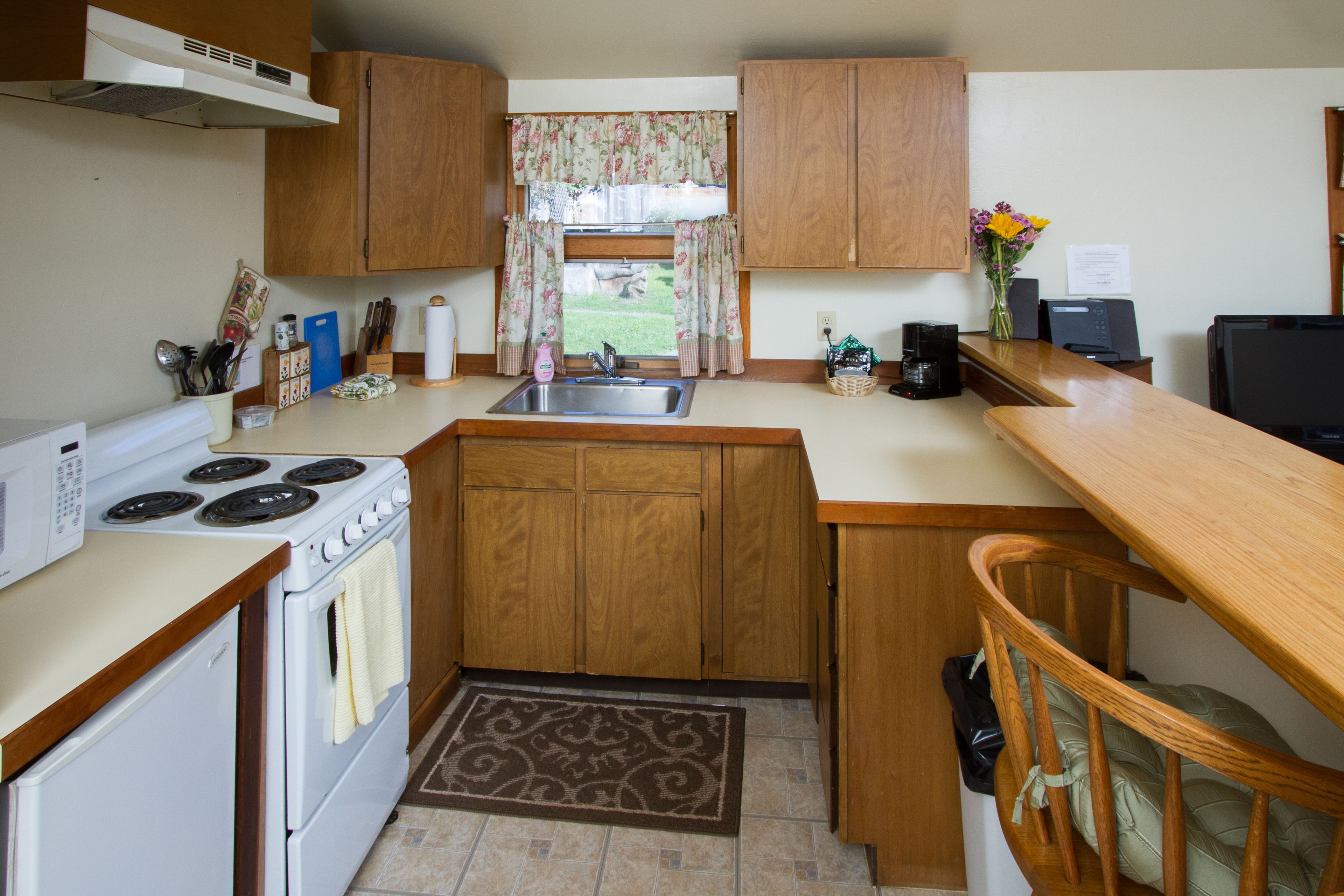 A compact kitchen with wooden cabinets, a stove, and a sink.