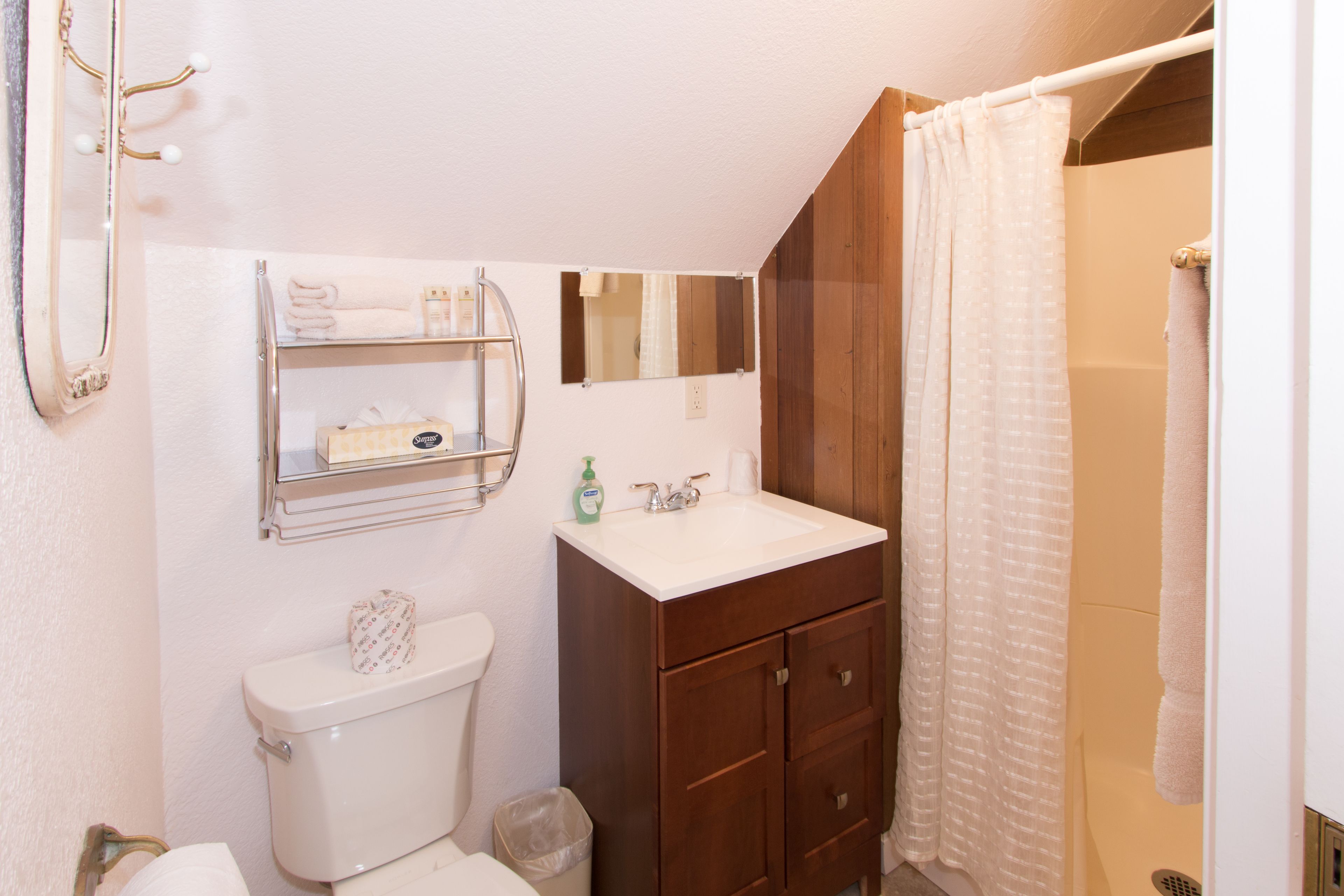 A bathroom with a toilet, sink, mirror, and shower curtain.