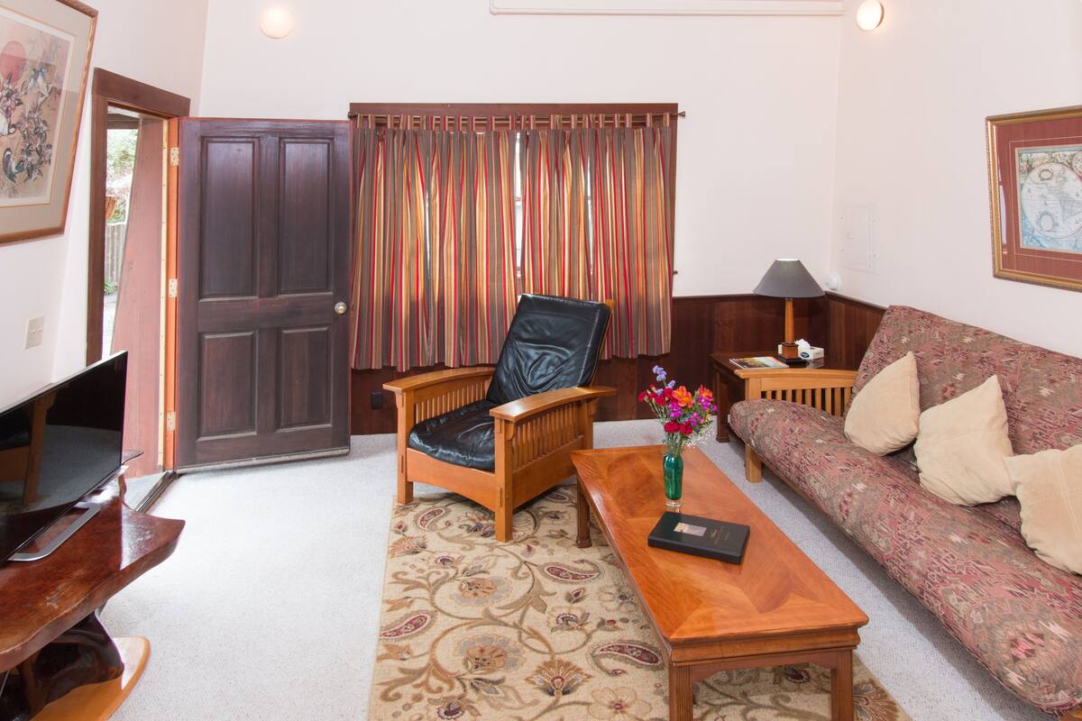A living room with a wooden chair, a sofa, a coffee table, and a TV.