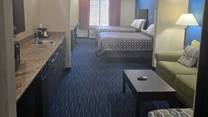 A hotel room with two beds, a desk, a chair, a sofa, and a small table. - Karnes City Lodge  (Karnes City)