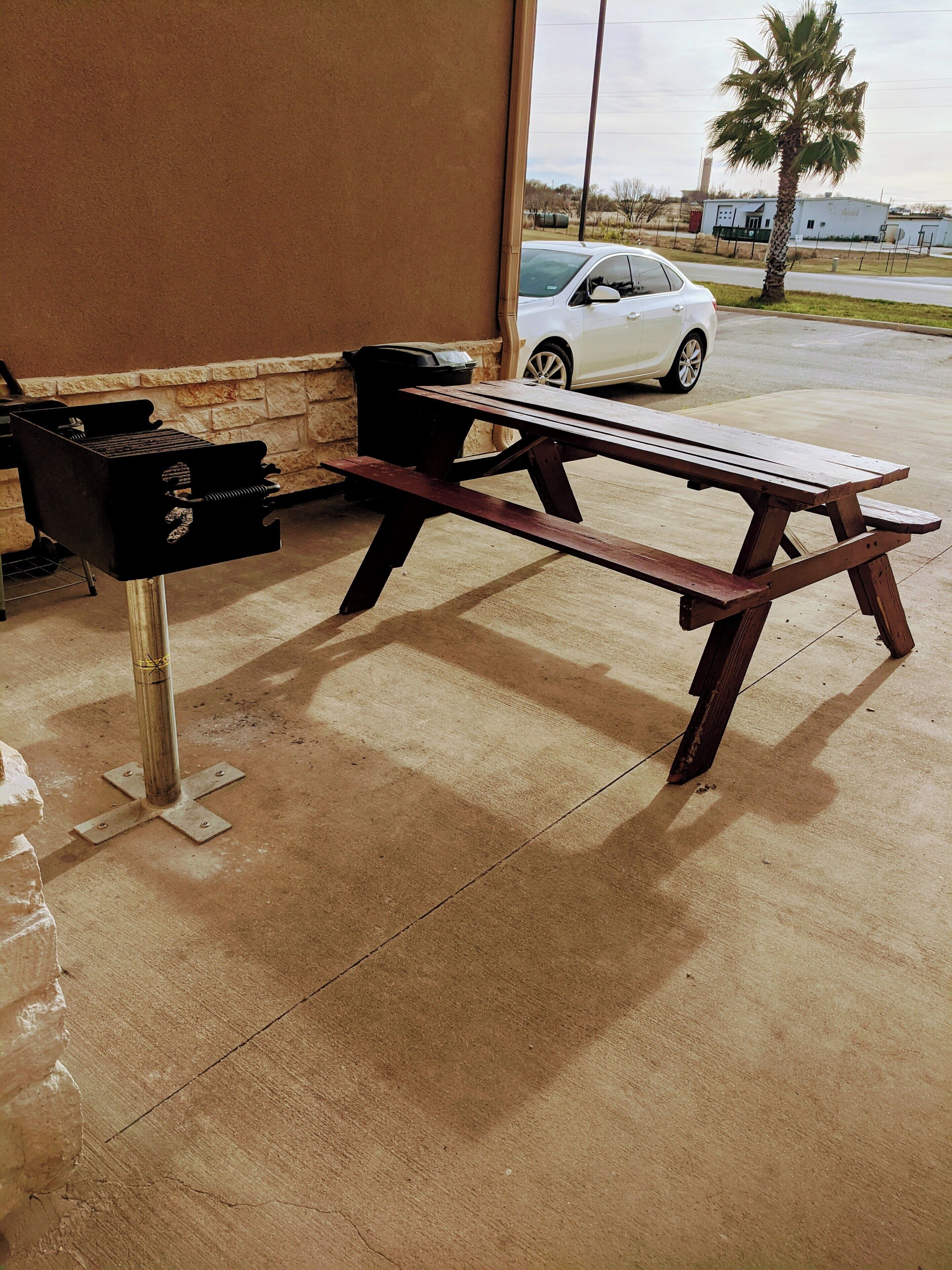 Eine Beton-Terrasse mit einem Holztisch und einem Grill.