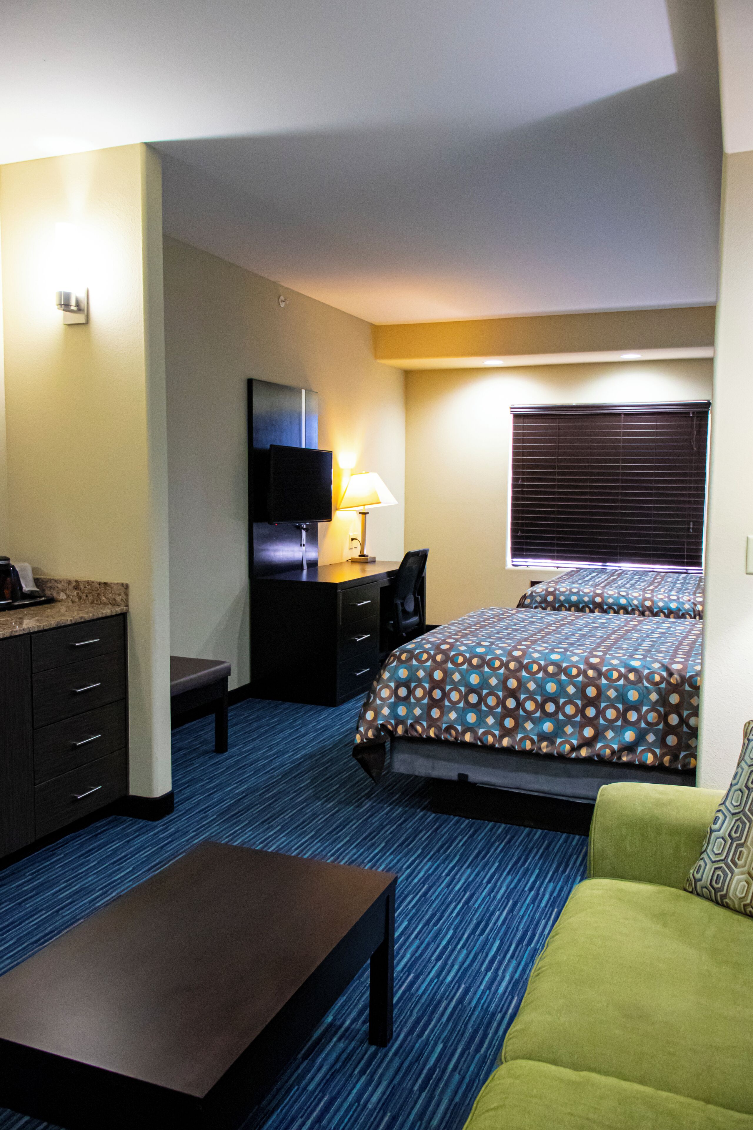 Habitación de hotel con cama, escritorio, silla, televisión y sofá.