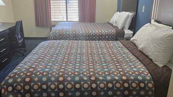 A hotel room with two beds, a desk, and a window with curtains.