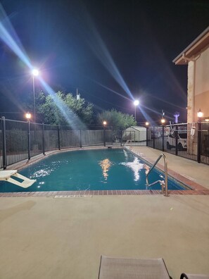 An indoor swimming pool with a metal fence, a ladder, and a lifeguard chair. - Karnes City Lodge  (Karnes City)