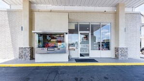 A building entrance with a glass door, a brick wall, and a stone base. - Motel 6 Van Buren, AR (Van Buren)