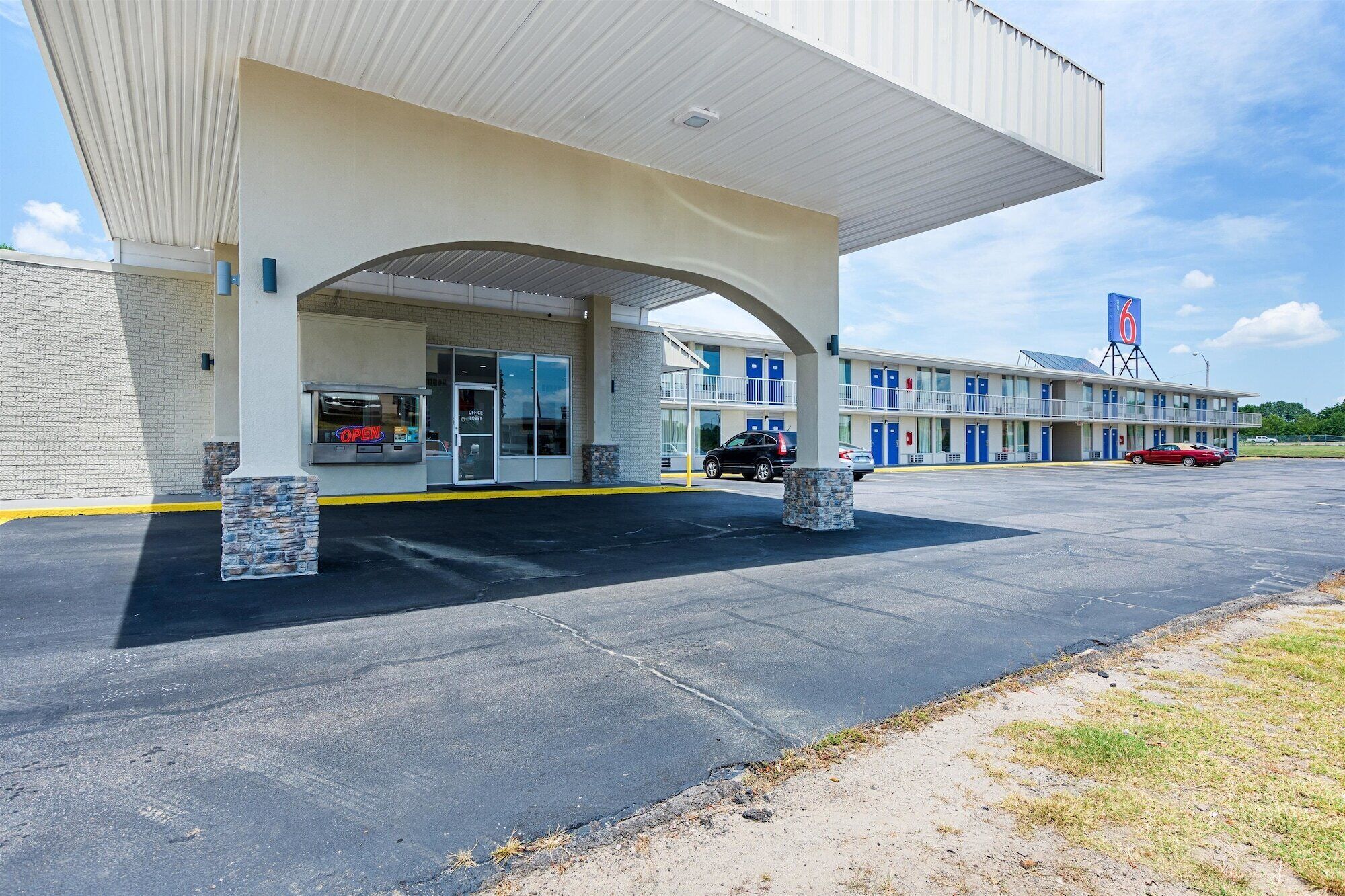A motel with a gas station attached, featuring a large canopy over the entrance, multiple rooms with balconies, and a prominent '6' sign on the building.