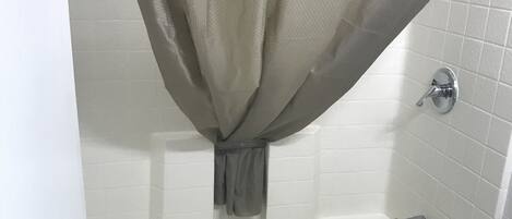 A bathroom with a bathtub, toilet, and a shower curtain.