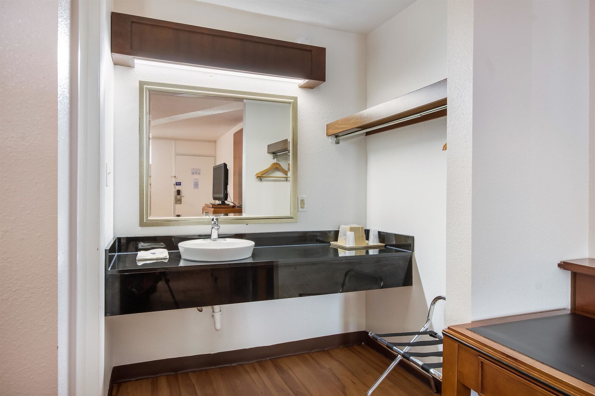 Une salle de bain avec un comptoir noir, un lavabo blanc, un miroir, un porte-serviettes et une table de billard.