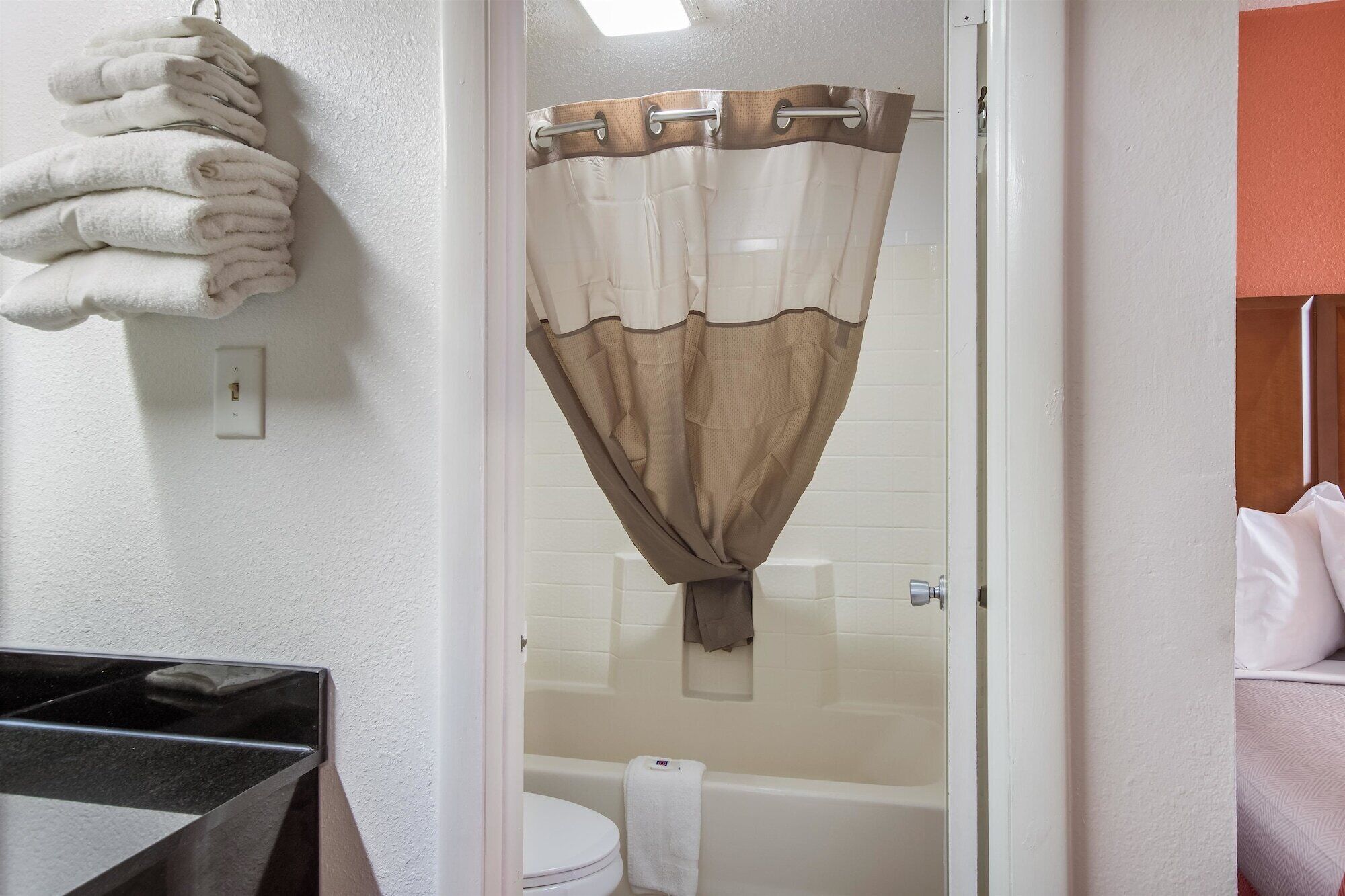A bathroom with a shower curtain, a toilet, and a towel rack.