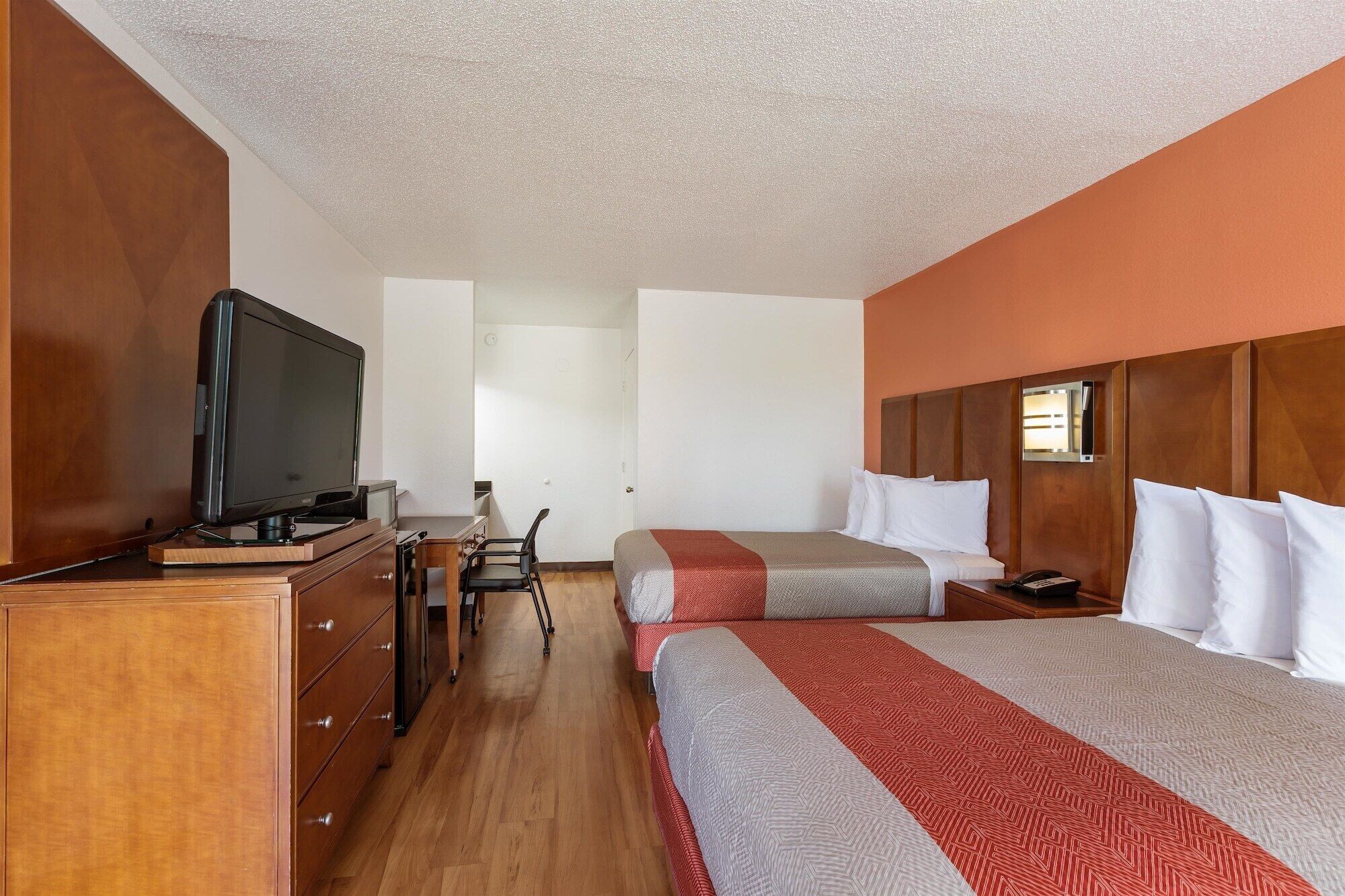 Une chambre d’hôtel avec deux lits, une télévision, un bureau et une chaise.