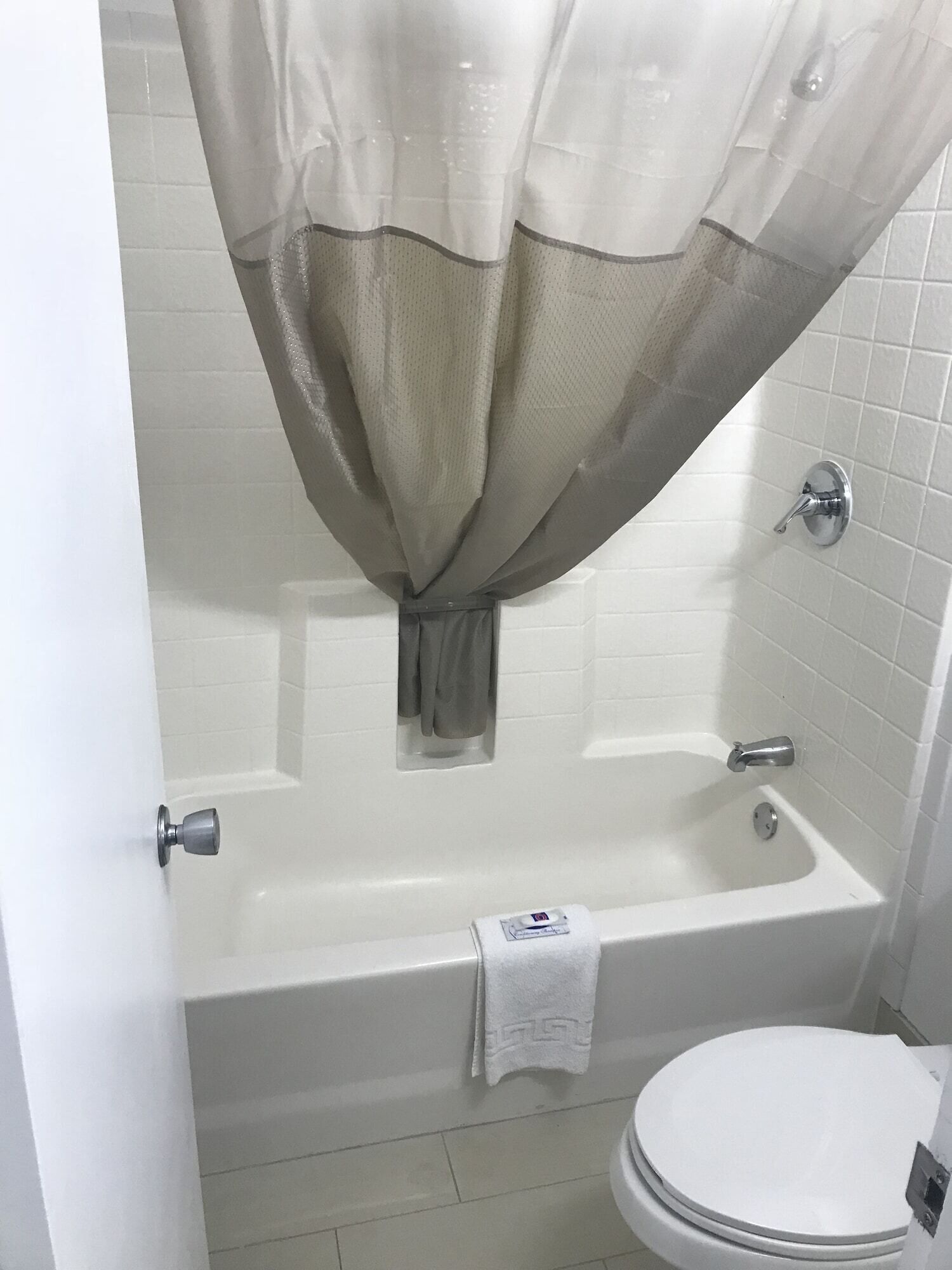 A bathroom with a bathtub, toilet, and a shower curtain.