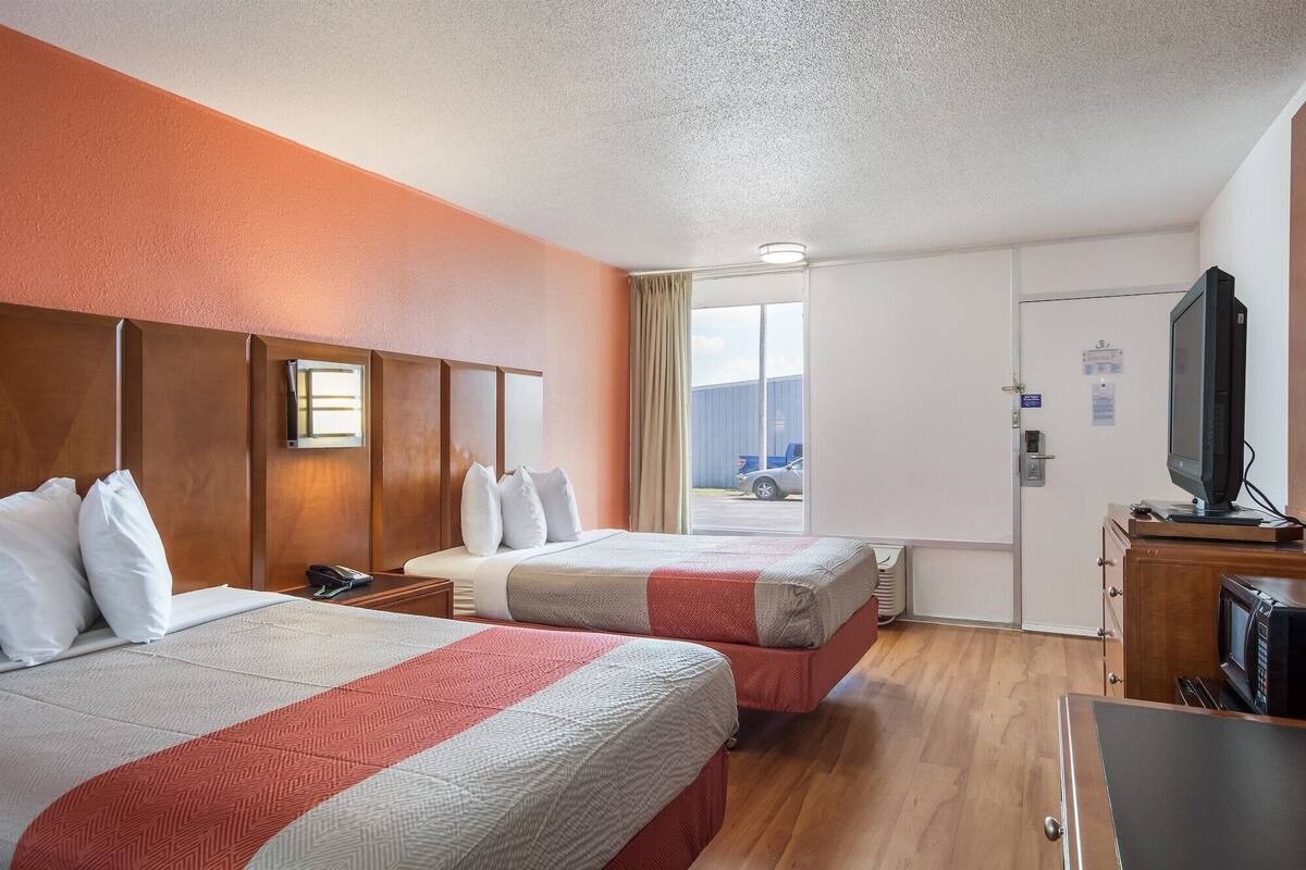 Une chambre d’hôtel avec deux lits, une télévision et une porte donnant sur un balcon.