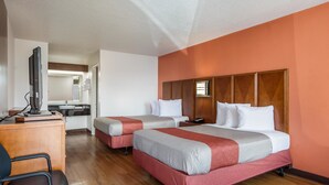 A hotel room with two beds, a desk, a television, and a bathroom visible through an open door. - Motel 6 Van Buren, AR (Van Buren)